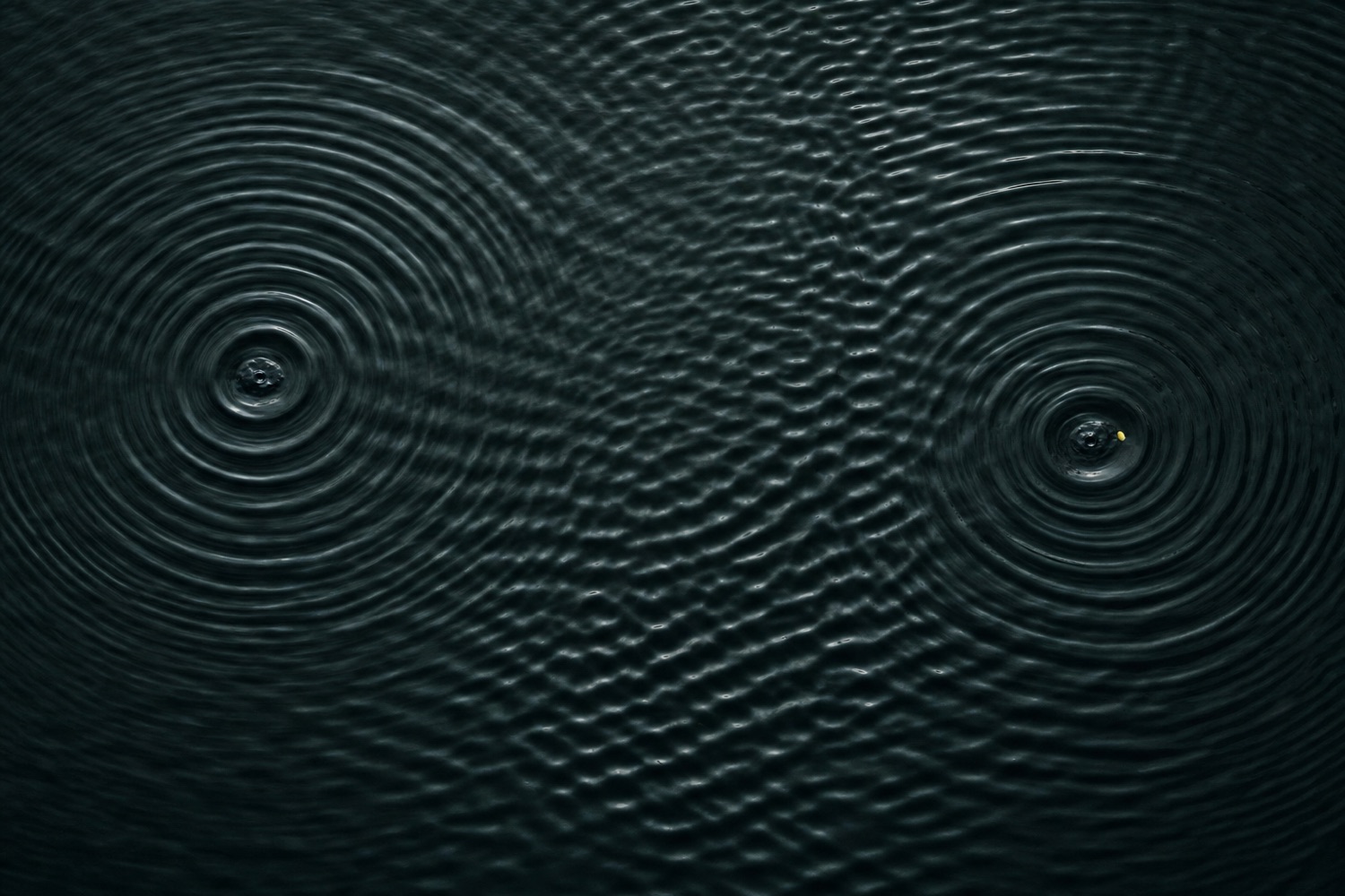 Zwei Wellenfelder auf dunklem Wasser, die sich in der Mitte überlagern